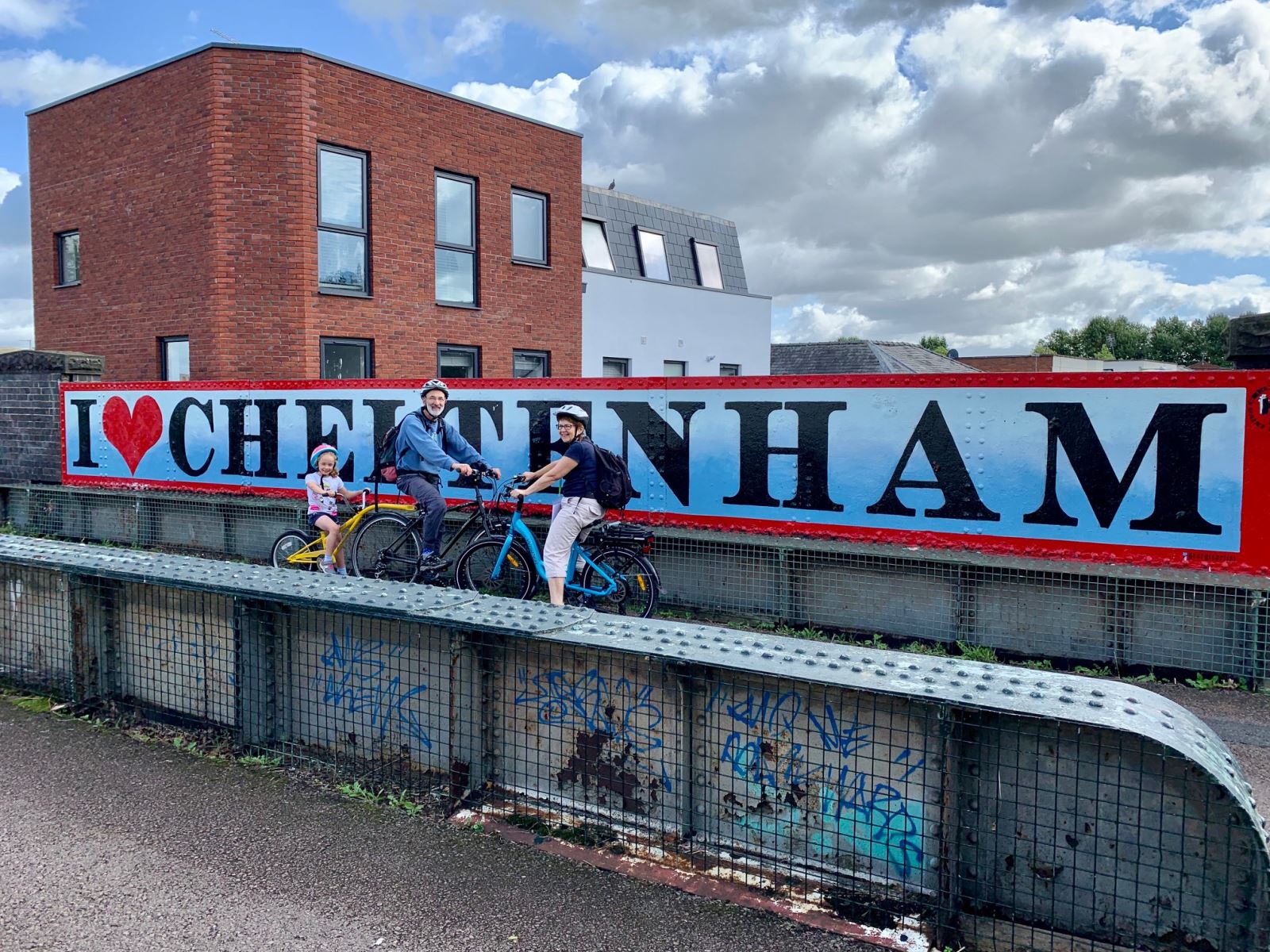 Family on bikes in front of the I Love Cheltenham graffiti on the Honeybourne Line